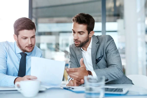 Analyseren van de gegevens. Gesneden foto van twee jonge zakenmannen met behulp van een laptop tijdens het doorlopen van papierwerk samen in een modern kantoor. — Stockfoto