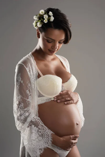 Olhando para baixo em vidas bela criação. Estúdio tiro de uma bela jovem grávida posando contra um fundo cinza. — Fotografia de Stock