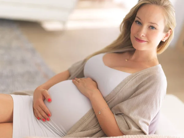 하루가 거의 다 됐어. 집 소파에 앉아 있는 아름답고 임신 한 젊은 여성의 모습. — 스톡 사진