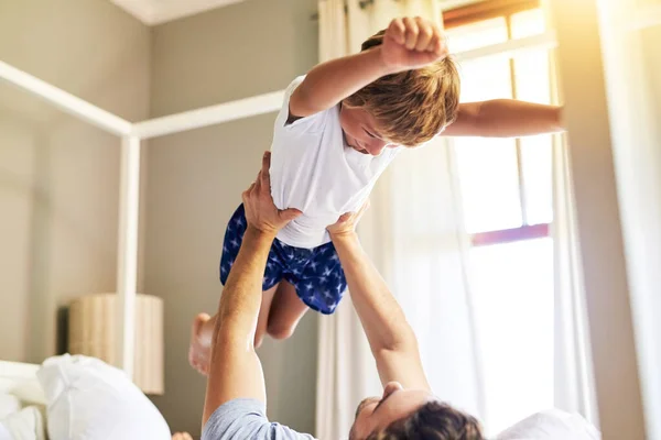Час літати. Знімок веселого маленького хлопчика, якого підхопив батько під час гри вдома вранці . — стокове фото
