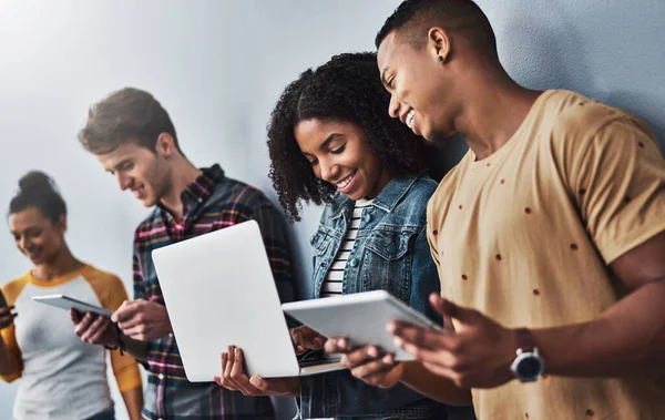 Blijf die verbinding delen. Studio shot van een groep jongeren met draadloze technologie tegen een grijze achtergrond. — Stockfoto