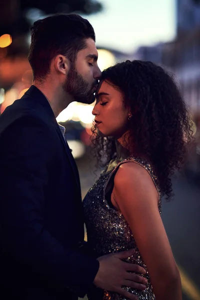 Особые моменты любви. Выстрел веселой молодой пары, держащей друг друга во время поцелуя в лоб на улице ночью. — стоковое фото
