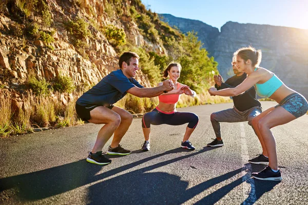 Theyve got their own warmup routine. Shot of a fitness group stretching before a run outside. — Stock Photo, Image