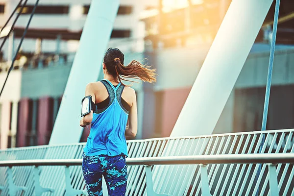 Run while you can. Shot of a young woman out in the city for her morning run. — Stock Photo, Image