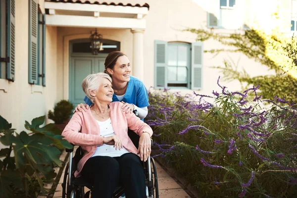 リラックスした生活を送る先輩の年を過ごす。車椅子の高齢患者と一緒に外の若い女性看護師の作物のショット. — ストック写真