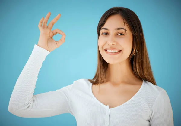 Alright with me. Studio shot of a young woman showing an OK against a blue background. — Stock Photo, Image