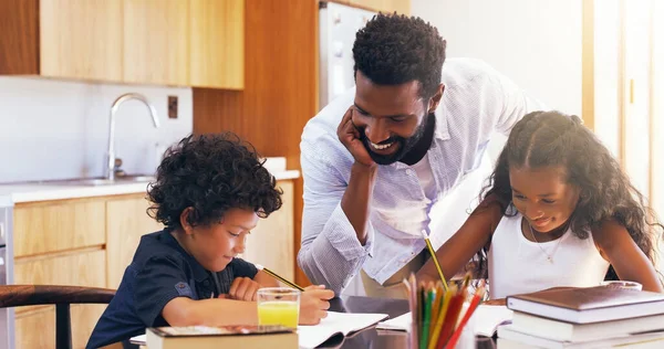 Vocês os dois estão a fazer um bom trabalho, continuem. Tiro recortado de um jovem pai ajudando seu adorável filho e filha com seus trabalhos escolares em casa. — Fotografia de Stock