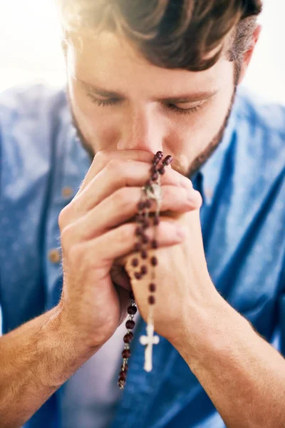 Il donne la priorité à sa foi. Plan recadré d'un jeune homme tenant son chapelet tout en priant. — Photo