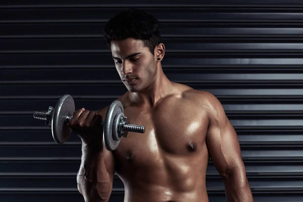 Building his body. Cropped shot of an athletic young man working out with a dumbbell. — Stock Photo, Image