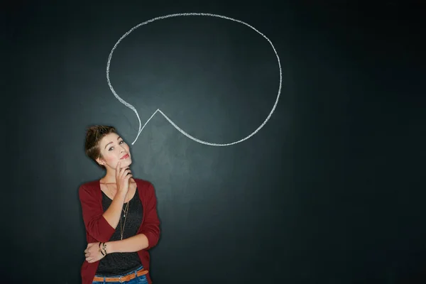 Whats your truth. Studio shot of a young woman posing with a chalk illustration of a speech bubble against a dark background.