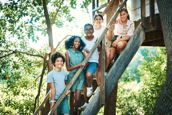 I campeggiatori felici vivono qui. Girato di un gruppo di adolescenti in piedi accanto a una casa sull'albero al campo estivo. — Foto Stock