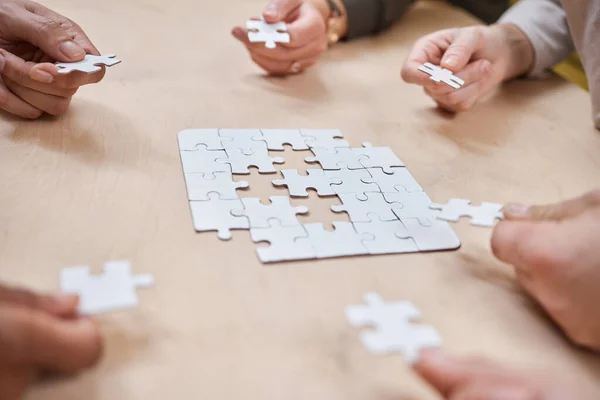 L'entreprise est un jeu de stratégie et d'innovation. Coup de feu recadré d'un groupe méconnaissable de gens d'affaires blottis ensemble et faire un puzzle dans le bureau. — Photo