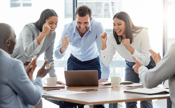Podemos hacer esto. Disparo de un grupo de empresarios animando mientras utilizan un ordenador portátil en una oficina en el trabajo. — Foto de Stock