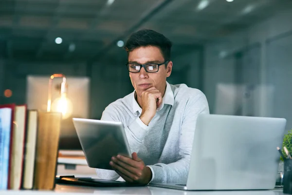 그는 그 일에 전념하고 있다. 한 잘생긴 젊은 사업가가 밤에 사무실에서 디지탈 태블릿을 사용하는 모습을 찍은 사진. — 스톡 사진