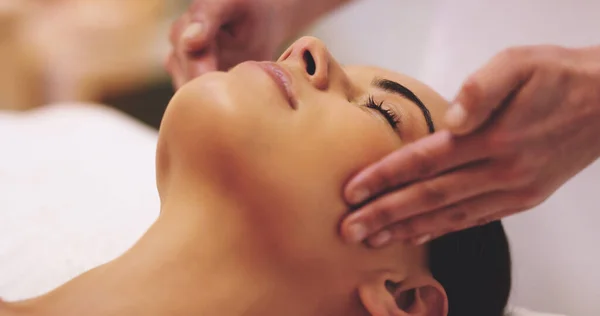 My mind is finally at ease. Shot of a beautiful young woman enjoying a head massage at a beauty spa. — Stock Photo, Image