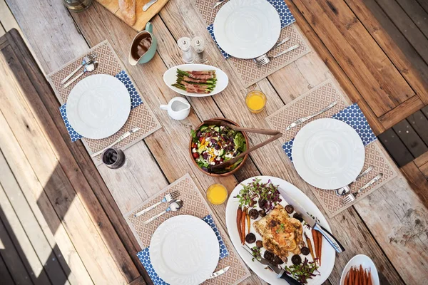 Refeições especiais que reúnem as pessoas. Tiro de ângulo alto de uma configuração de mesa com comida e bebidas ao ar livre. — Fotografia de Stock