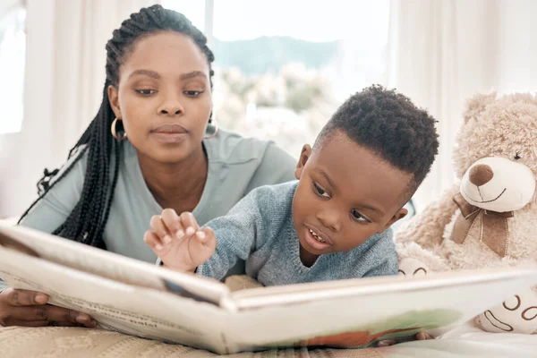 Lezen met mama. Gehakt schot van een schattige kleine jongen en zijn moeder lezen een boek op een bed thuis. — Stockfoto