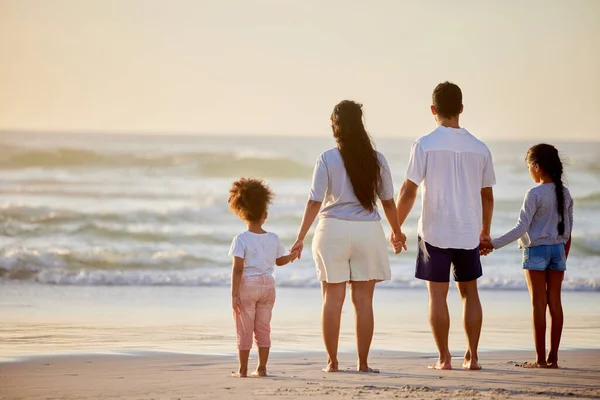 Šťastná rodina je jen dřívější nebe. Fotka rodiny, jak sleduje západ slunce na pláži. — Stock fotografie