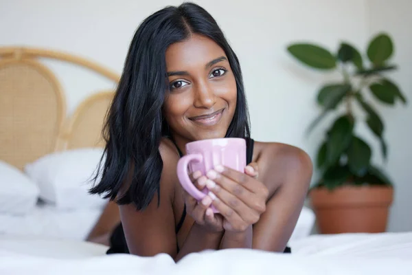 それは私と私の好きな飲み物です。ベッドの上に横になっている間にカップを持っている美しい若い女性のショット. — ストック写真