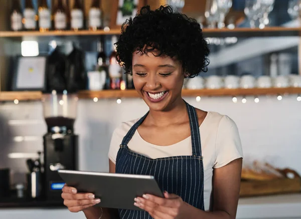 Taking advantage of technological tools to boost sales. Shot of a young woman using a digital tablet while working in a cafe.