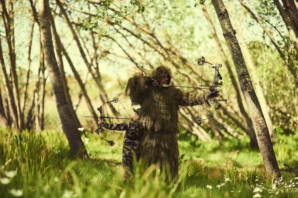 Its all about aim. Shot of a father and son in camouflage hunting with bows and arrows in the woods. — Stock Photo, Image