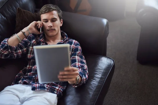 No pewnie. Właśnie się loguję. Wysoki kąt ujęcia przystojnego młodego mężczyzny używającego tabletu i komórki podczas siedzenia na kanapie w domu. — Zdjęcie stockowe