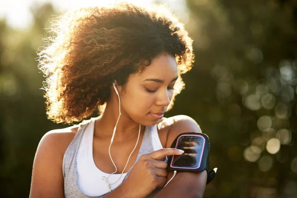 Wybierz playlistę, która cię nakręci. Strzał atrakcyjnej młodej kobiety słuchającej muzyki podczas ćwiczeń na świeżym powietrzu. — Zdjęcie stockowe