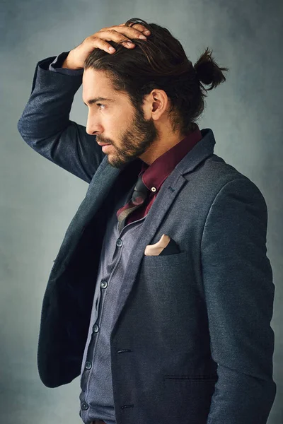 Style from the head down. Studio shot of a stylishly dressed handsome young man standing with his hand in his hair. — Stock Photo, Image