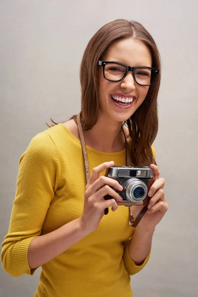 Jag har några bra bilder. Studio porträtt av en attraktiv ung kvinnlig fotograf poserar med sin kamera mot en grå bakgrund. — Stockfoto