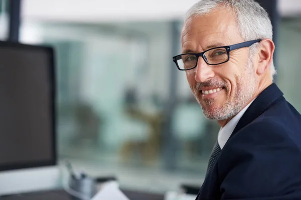 Tengo el éxito cubierto. Retrato de un hombre de negocios maduro sonriente trabajando en su escritorio en una oficina. —  Fotos de Stock