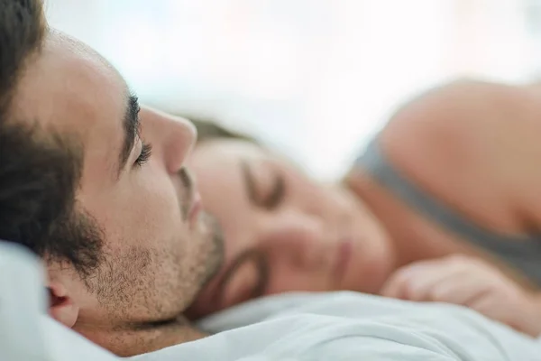 Иметь кого-то, с кем можно разделить свою жизнь прекрасно. Съемка расслабленной молодой пары, спящей в постели вместе дома. — стоковое фото