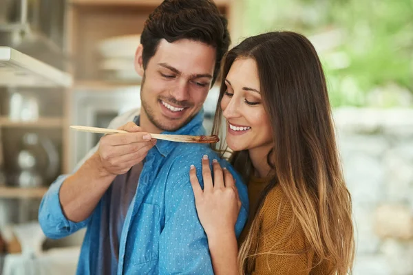 Diz-me o que achas... Tiro de um jovem bonito dando a sua namorada um gosto do que ele cozinha. — Fotografia de Stock