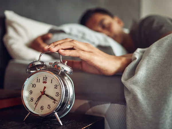 Nur noch fünf Minuten, sagte nie jemand. Aufnahme eines jungen Mannes, der nach seinem Wecker greift, nachdem er zu Hause im Bett aufgewacht ist. — Stockfoto