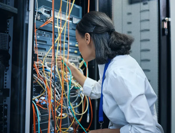 Sabe exactamente dónde debe estar cada cable. Imagen recortada de una atractiva joven programadora trabajando en una sala de servidores. — Foto de Stock