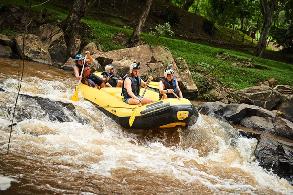 Navigating some tricky waters. High angle shot of a group of young friends white water rafting. — Stock Photo, Image