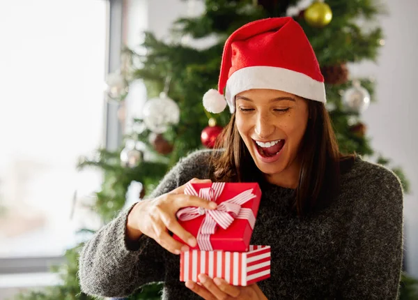 Kerstmis is de dag die alle tijd bij elkaar houdt. Foto van een jonge vrouw die cadeautjes opent tijdens Kerstmis thuis. — Stockfoto