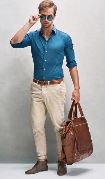 On his way in style. Full length portrait of a handsome young man posing with a bag in the studio. — Stock Photo, Image