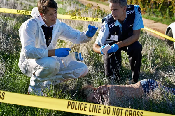 Examinando las pruebas. Disparo de dos investigadores examinando pruebas en la escena de un crimen. — Foto de Stock