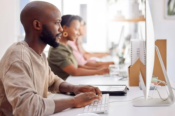 La pressione è sopra ed erano pronti per esso. Girato di un uomo d'affari che lavora al suo computer mentre i suoi colleghi siedono sullo sfondo. — Foto Stock