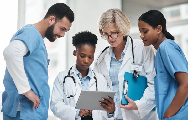 Ce sont les dossiers des patients actuels. Tournage d'un groupe de médecins utilisant une tablette numérique ensemble dans un hôpital. — Photo