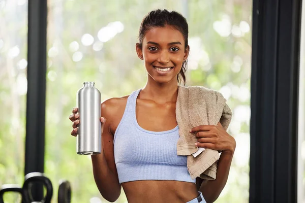 La mia salute è la mia priorità numero uno. Girato di una bella giovane donna che tiene la sua bottiglia d'acqua e asciugamano in palestra. — Foto Stock