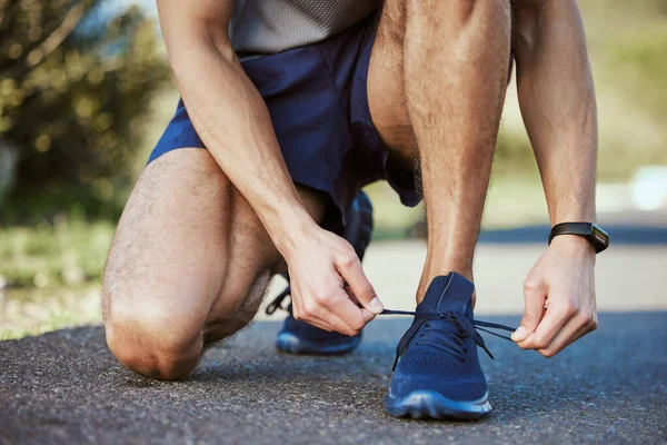 目標を持つ人々は、どこに行くかを知っているので成功します。屋外で運動している間に彼の靴ひもを結ぶ認識できない男の閉鎖ショット. — ストック写真