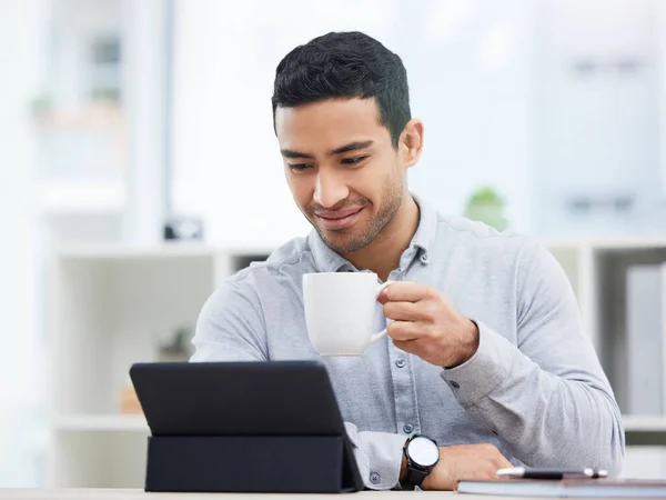 Myslím, že mám před sebou zajímavý den. Snímek mladého podnikatele, který pije kávu během používání svého digitálního tabletu. — Stock fotografie