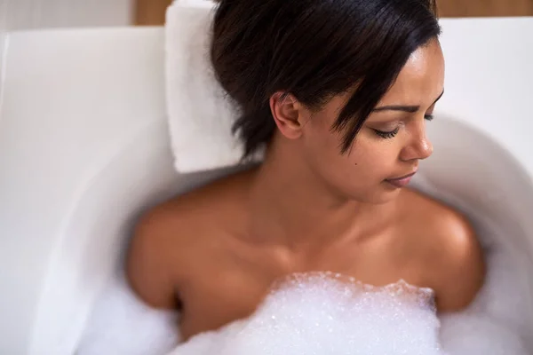 Deleitarse en un baño lleno de felicidad. Foto de una joven atractiva relajándose en un baño de burbujas. — Foto de Stock