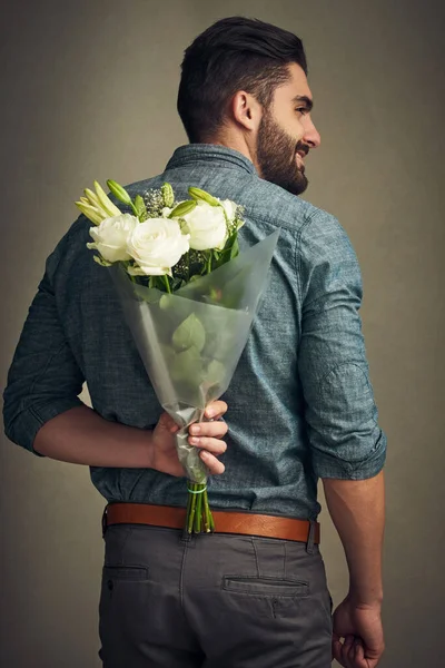Она заслуживает почувствовать себя особенной. Съемка красивого молодого человека, держащего букет цветов за спиной. — стоковое фото