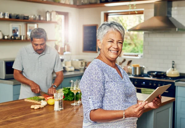 O chef de soux mais esperto que há. Retrato de uma mulher madura usando um tablet digital enquanto prepara uma refeição em casa com o marido. — Fotografia de Stock