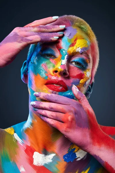 Bei Farbe geht es um Ausdruck. Studioaufnahme einer jungen Frau, die mit mehrfarbiger Farbe im Gesicht posiert. — Stockfoto