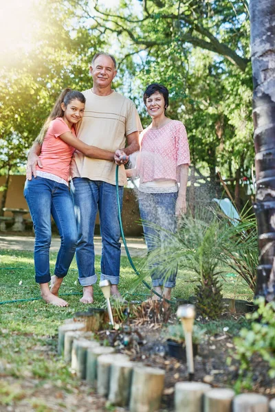 Одна велика щаслива сім'я. Портрет сім'ї, що поливає сад шлангом . — стокове фото