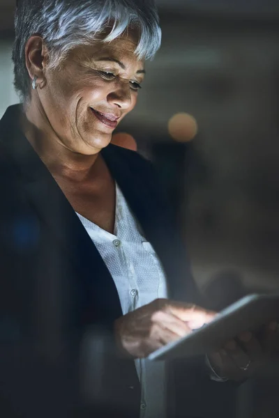 Hard werken ondersteund door slimme technologie. Foto van een volwassen zakenvrouw met behulp van een digitale tablet 's avonds laat in een modern kantoor. — Stockfoto