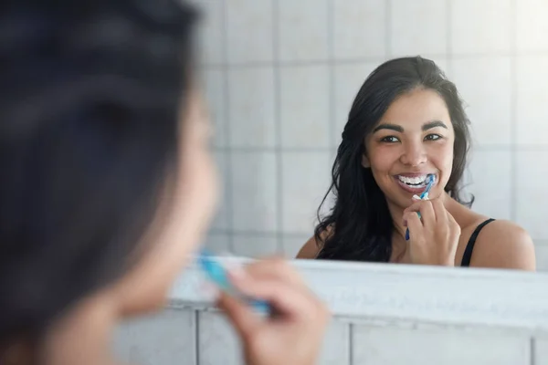 İnci gibi beyazlarıyla ilgileniyor. Çekici bir genç kadının banyoda dişlerini fırçalarken fotoğrafı.. — Stok fotoğraf